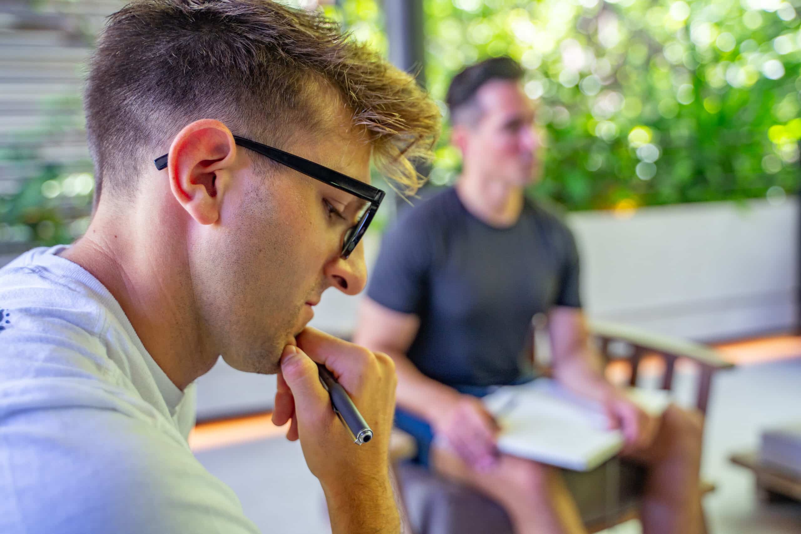 Notable CEO Sam Malik reflecting in the foreground with his journal while a facilitator is in the background